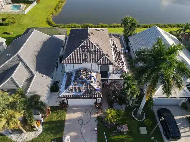 Elevated front view of stacked roof tiles and exposed battens above a garage beside a lakeside lawn in Delray Beach, photographed August 2026