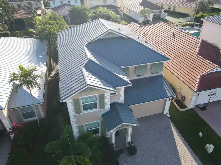 Silver metal roof on a two-story house beside neighboring homes in Royal Palm Beach, photographed December 2025